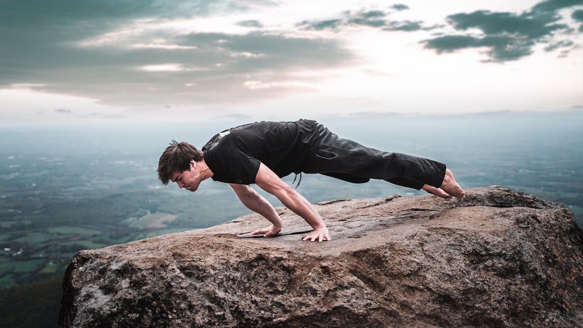 man in black t-shirt and black shorts sitting on brown rock formation during daytime